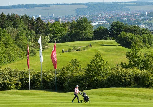 Frau auf dem Golfplatz mit Golftasche.